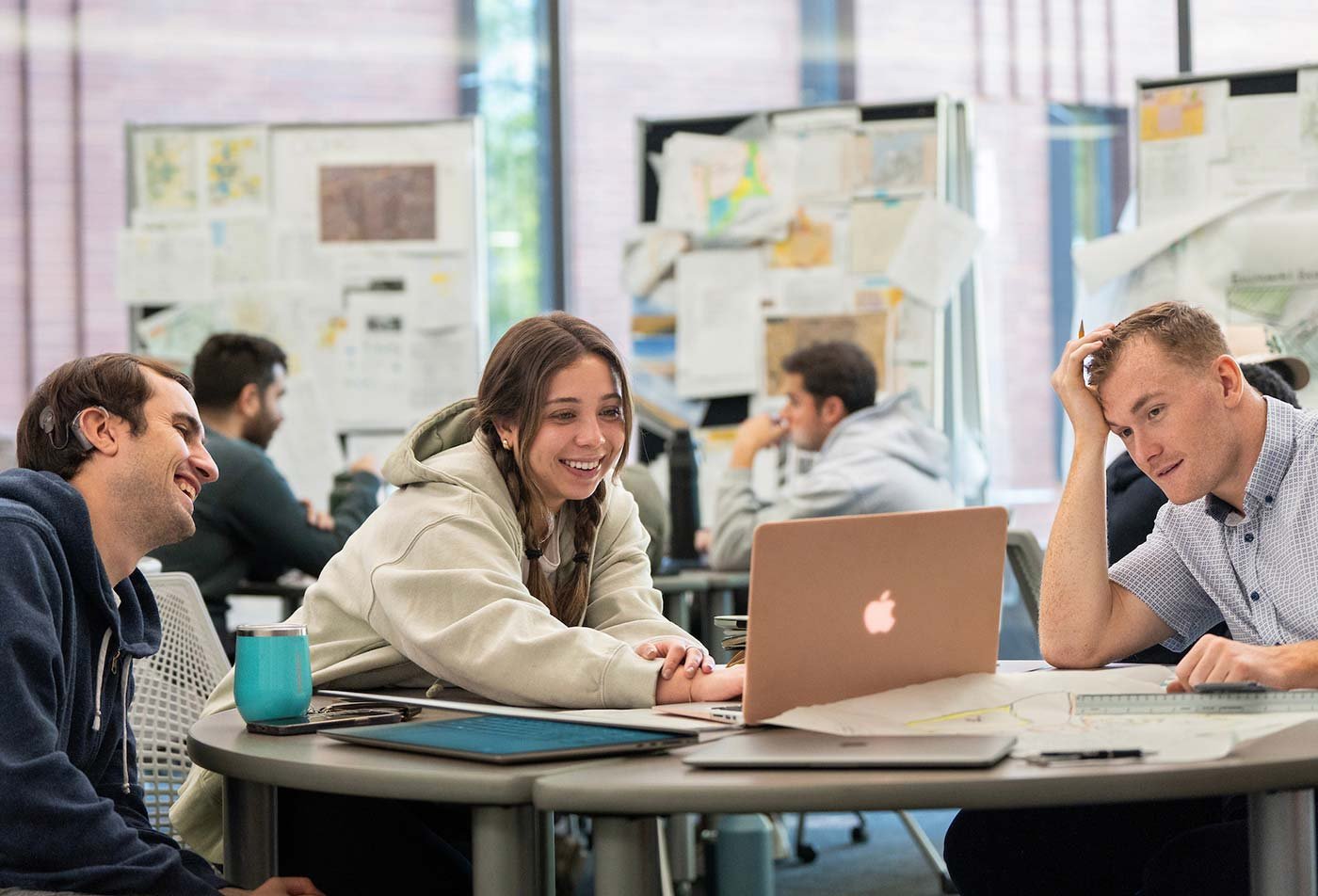Students work together on a project on a table filled with study material, demonstrating teamwork in ASU's Real Estate Development program.