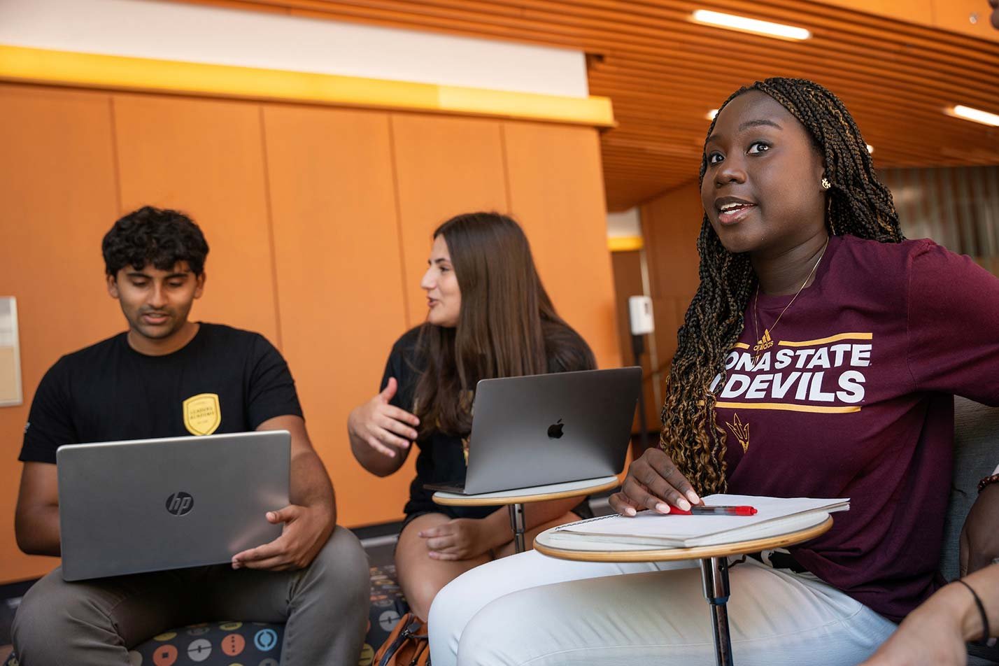 A group collaborates on laptops in a shared study area, illustrating teamwork in ASU's Business Administration concentration.