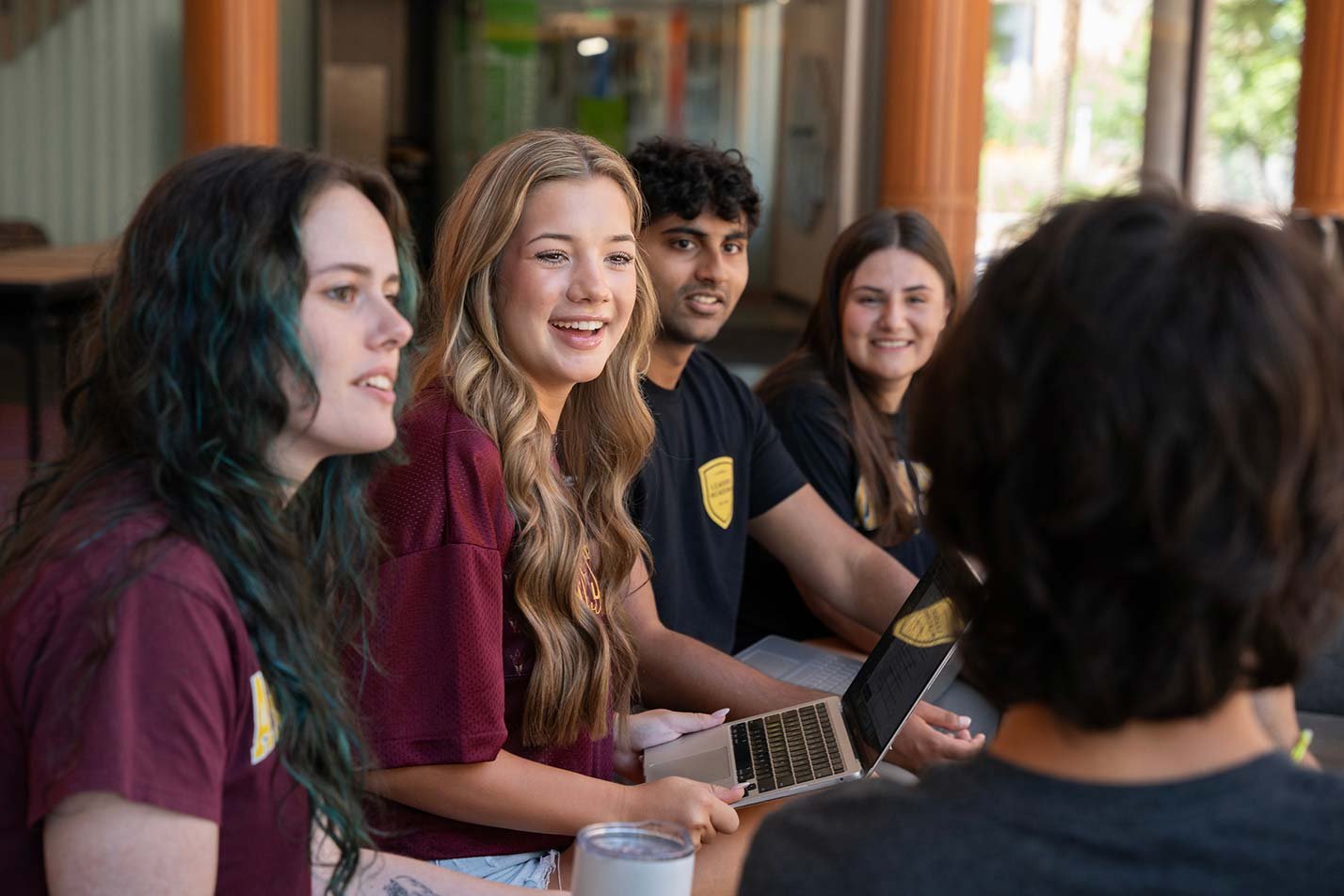 A collaborative discussion unfolds over a laptop, showcasing teamwork in ASU's Business Exploratory program.
