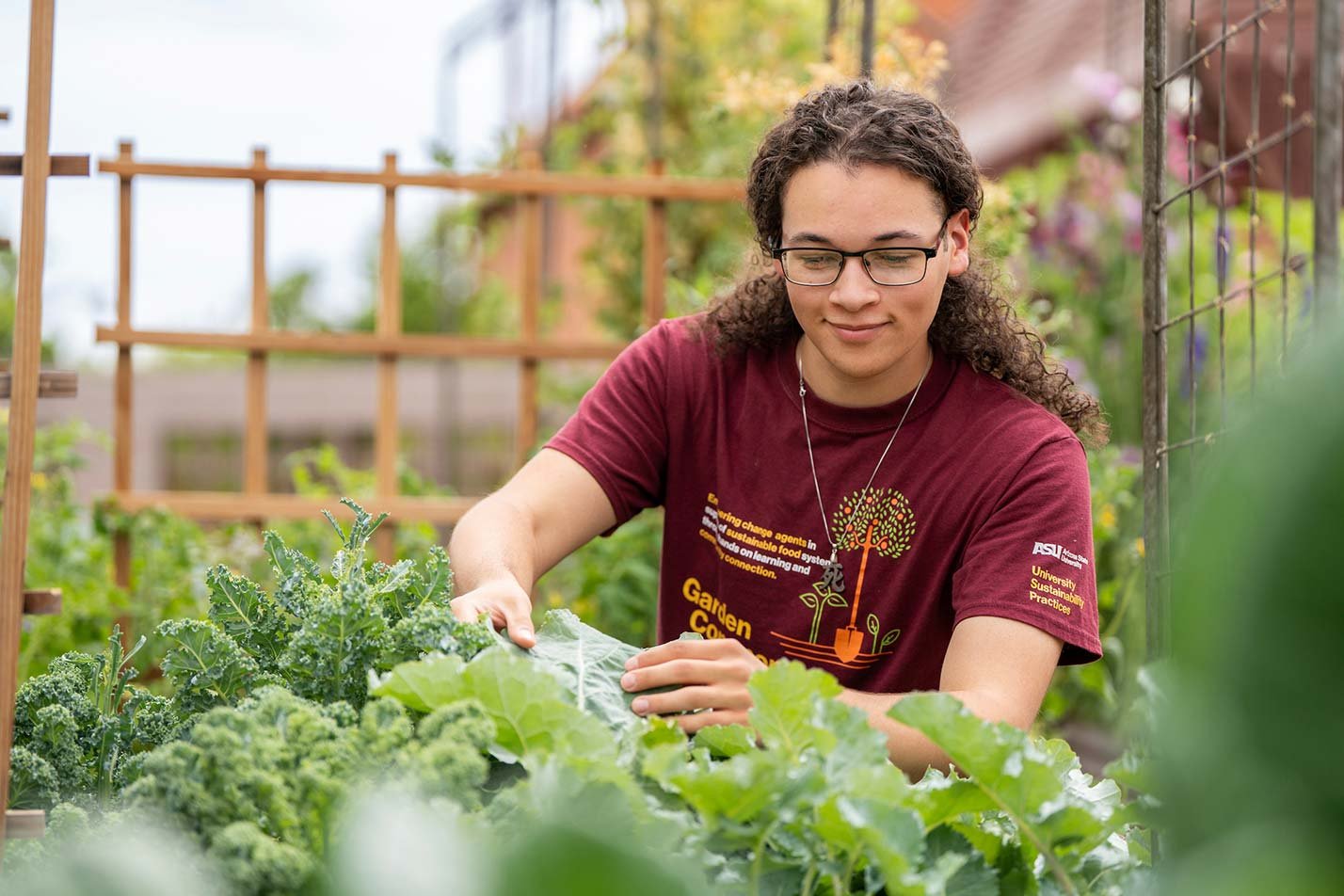 In a lush garden, a student carefully tends to plants, showcasing practical learning in ASU's Food Industry Management degree.