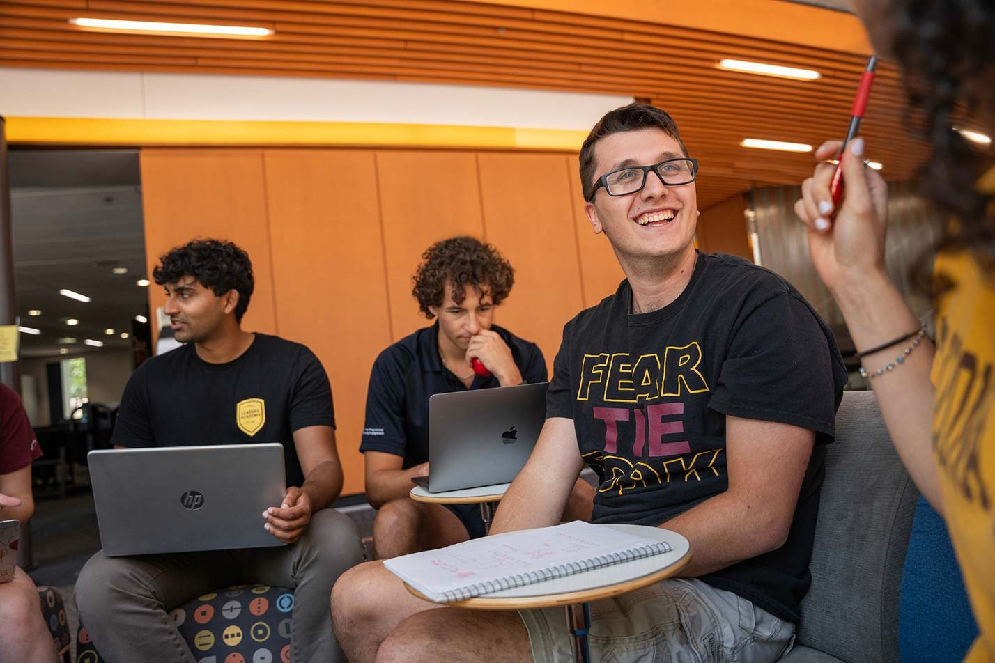 Smiling students share ideas in a modern study space, representing teamwork in ASU's BA in Business (Global Politics) degree.