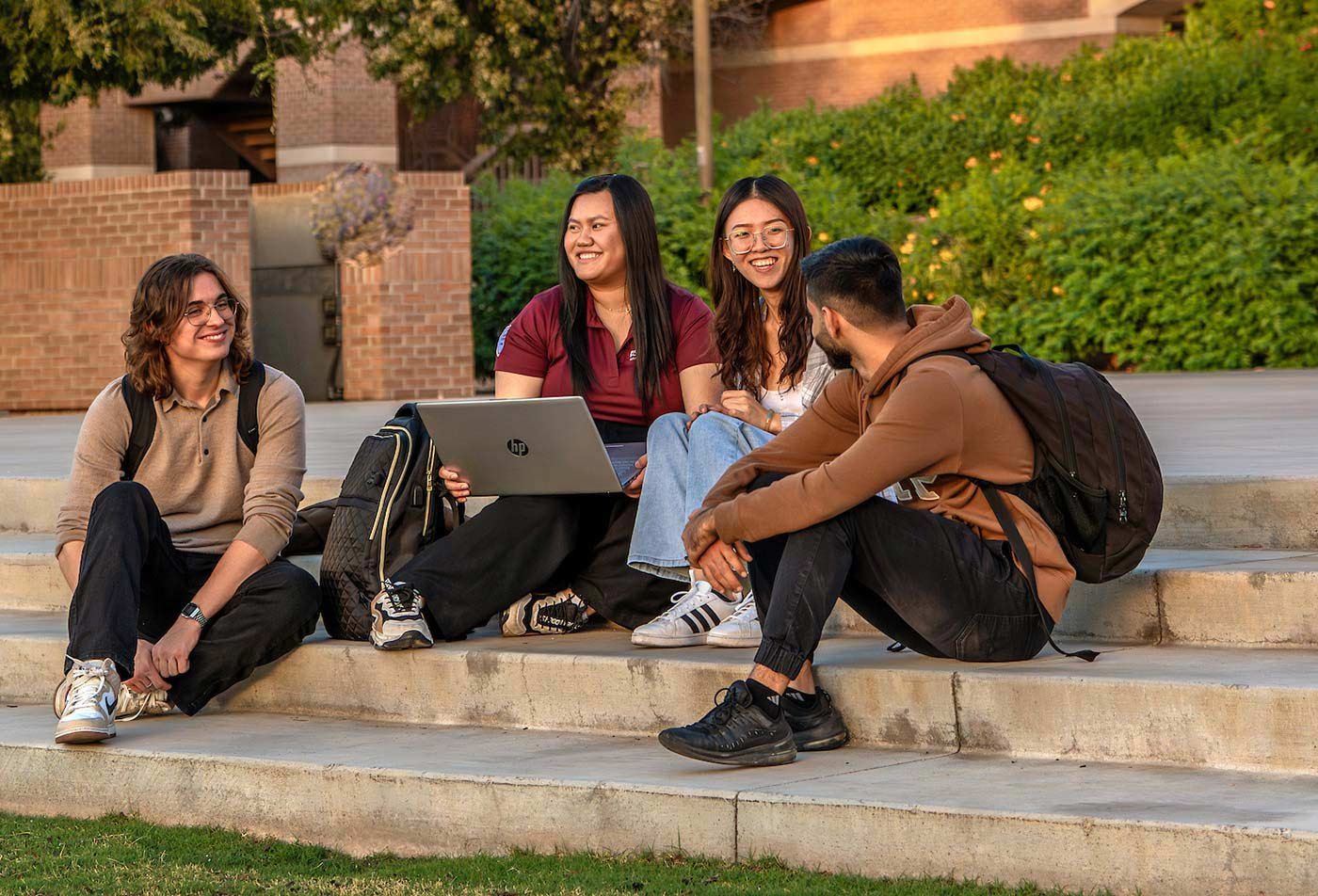 On outdoor campus steps, a laptop discussion highlights collaborative learning in ASU's Business (Health Care) degree.