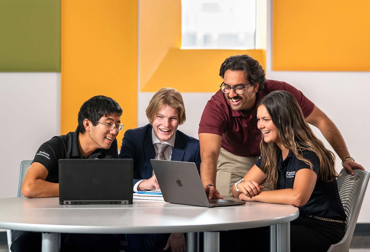 Around a table in a brightly lit room, students collaborate around laptops, illustrating teamwork and problem-solving in ASU's Business minor program.