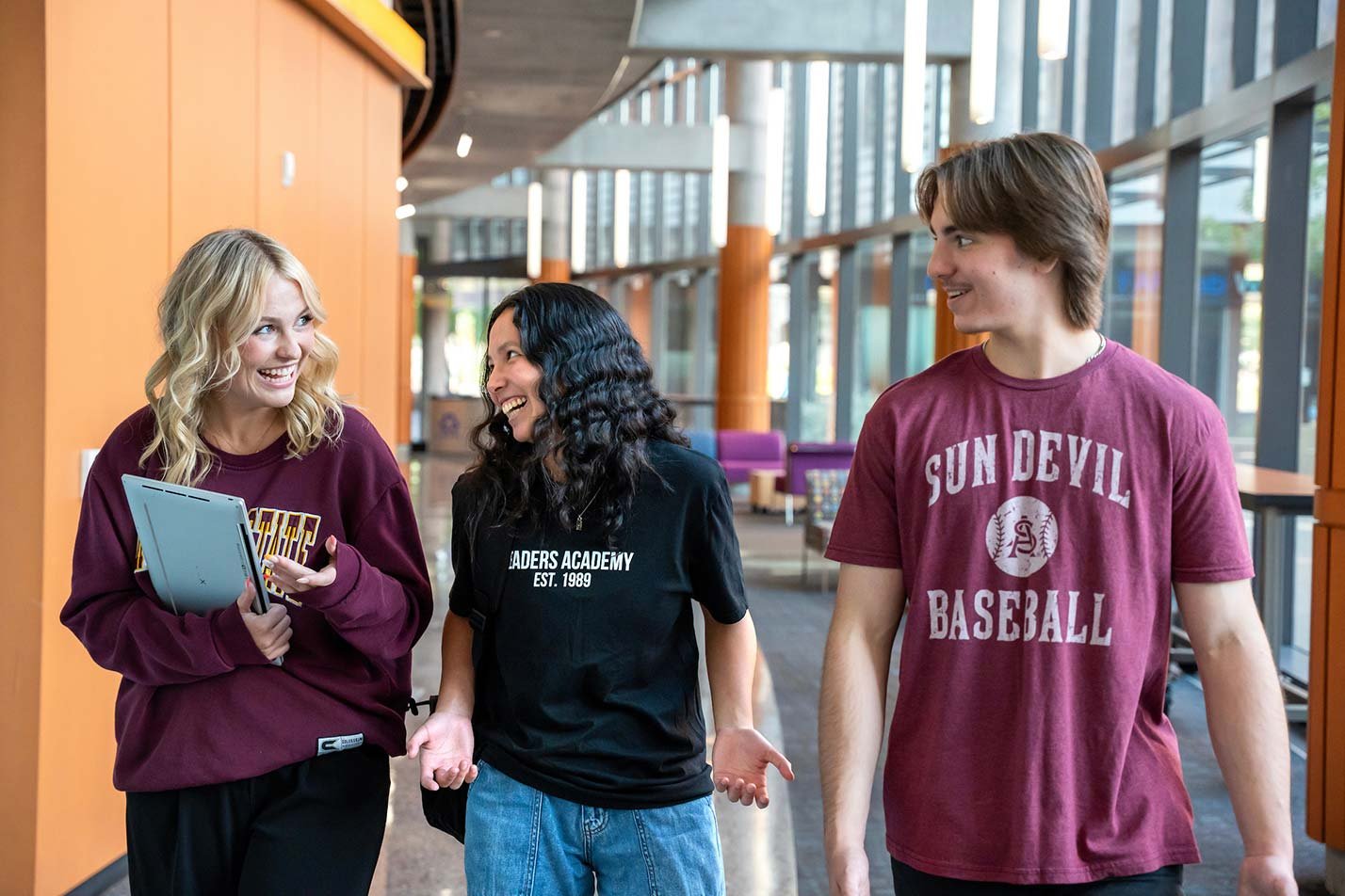 Students laugh as they walk along a campus hallway, showcasing camaraderie and community in ASU's Sports Business concentration.