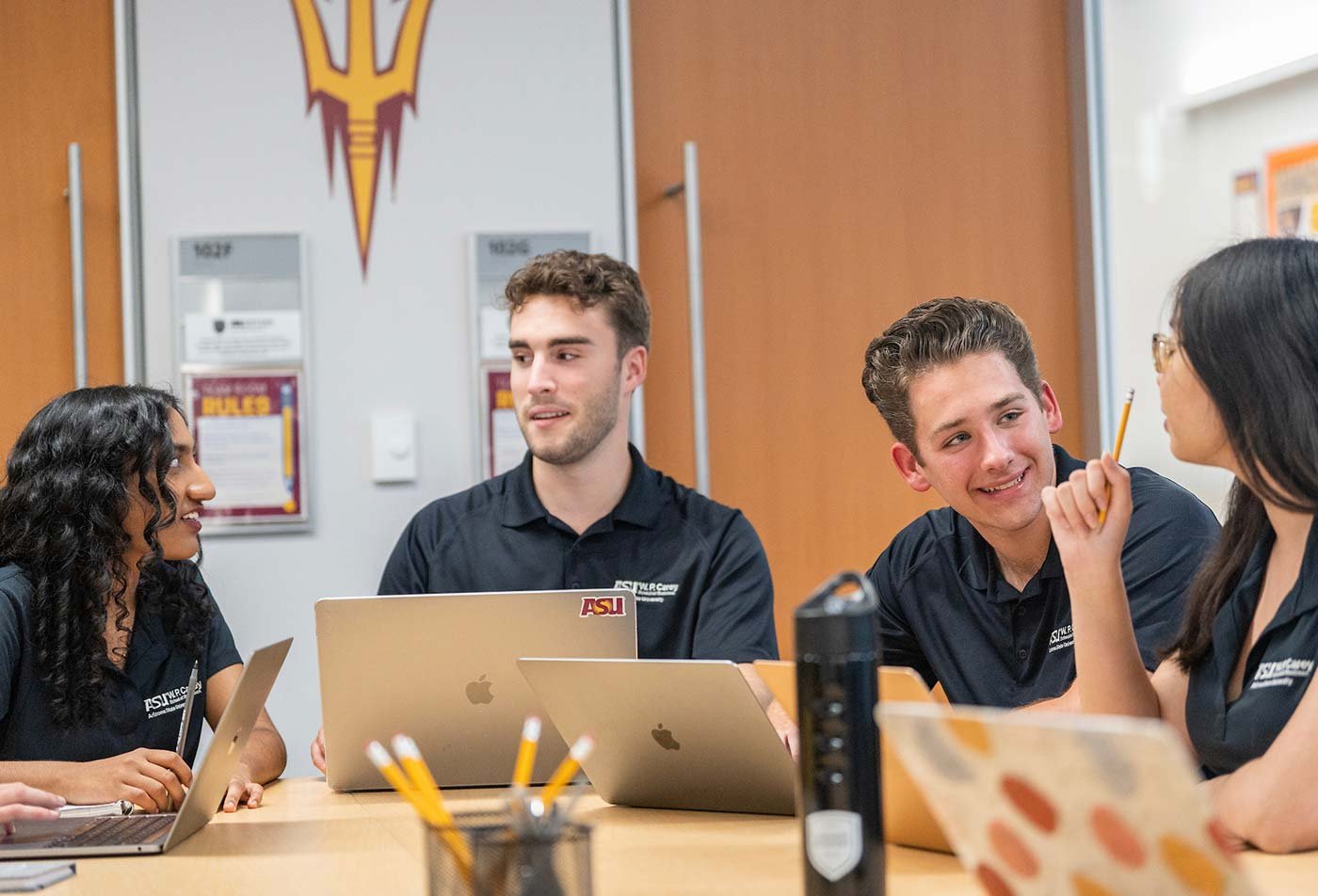 Students collaborate around a table, illustrating the valuable connections made through ASU's Business (Tourism) degree.