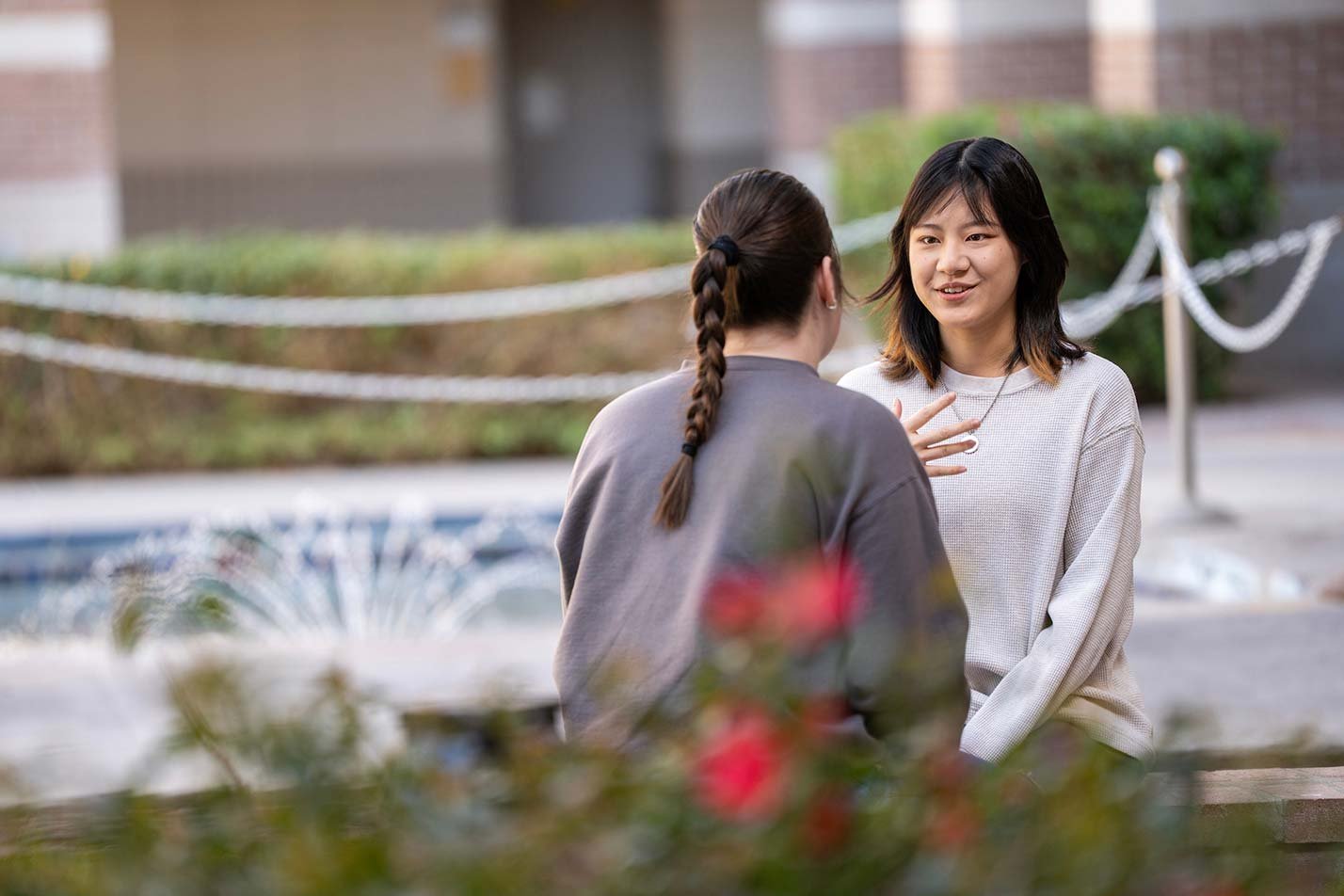 Amid greenery and a fountain, an outdoor chat illustrates communication skills vital in ASU's Business (Technology) degree.