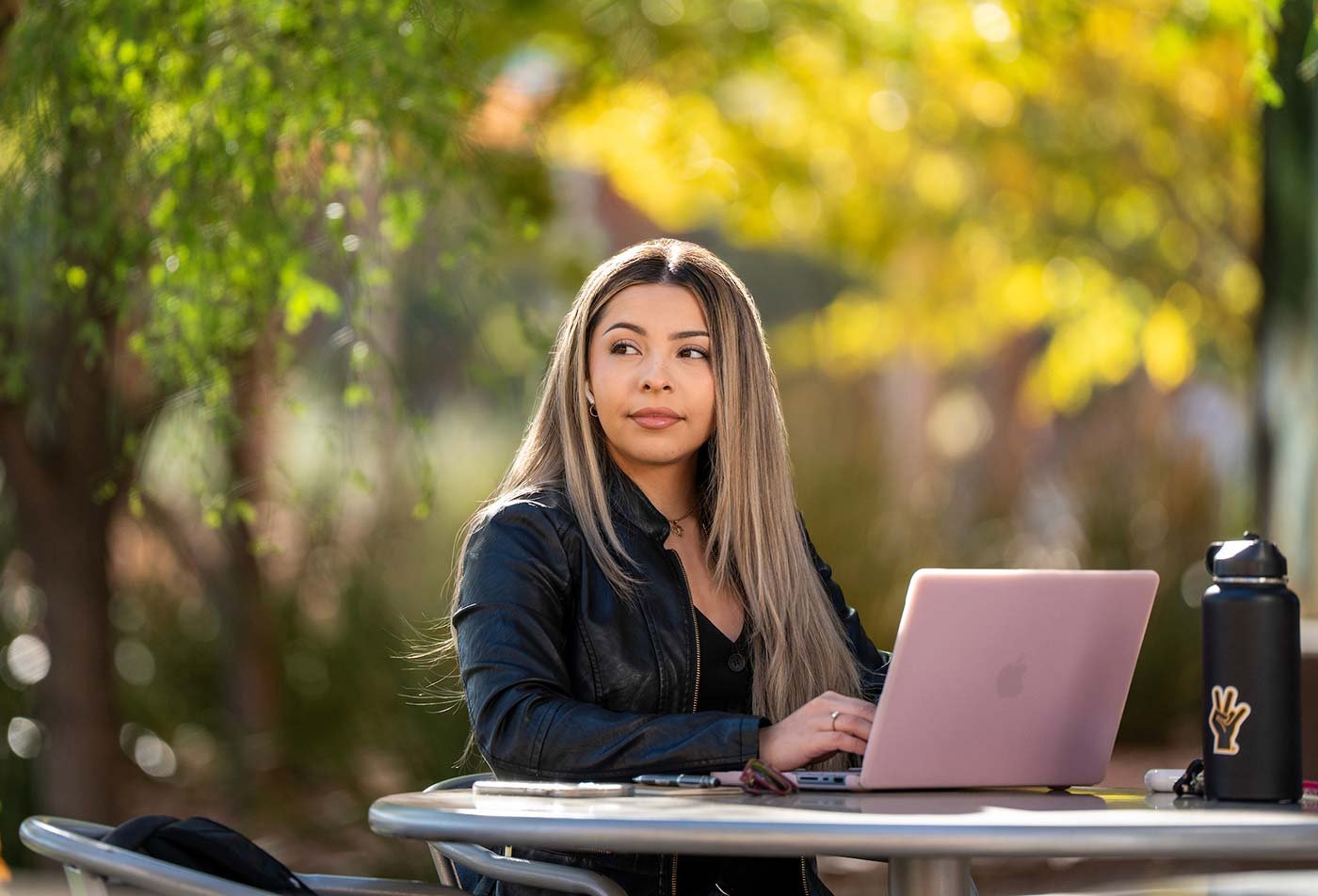 A young scholar works at an outdoor table, demonstrating engaging learning in ASU's Management, MS degree.