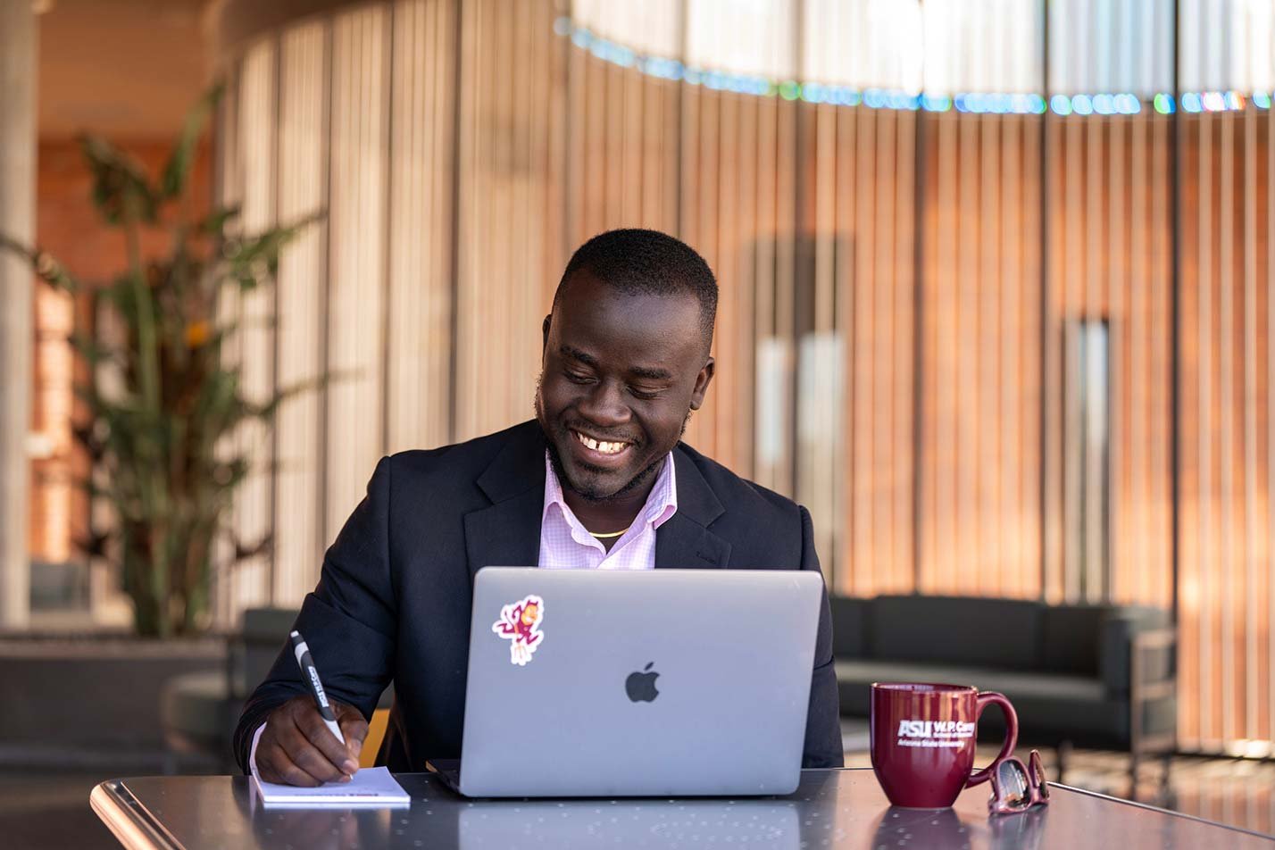 A student focuses on his work on a laptop in a modern study space, reflecting specialized learning in ASU's MS in Economics program.