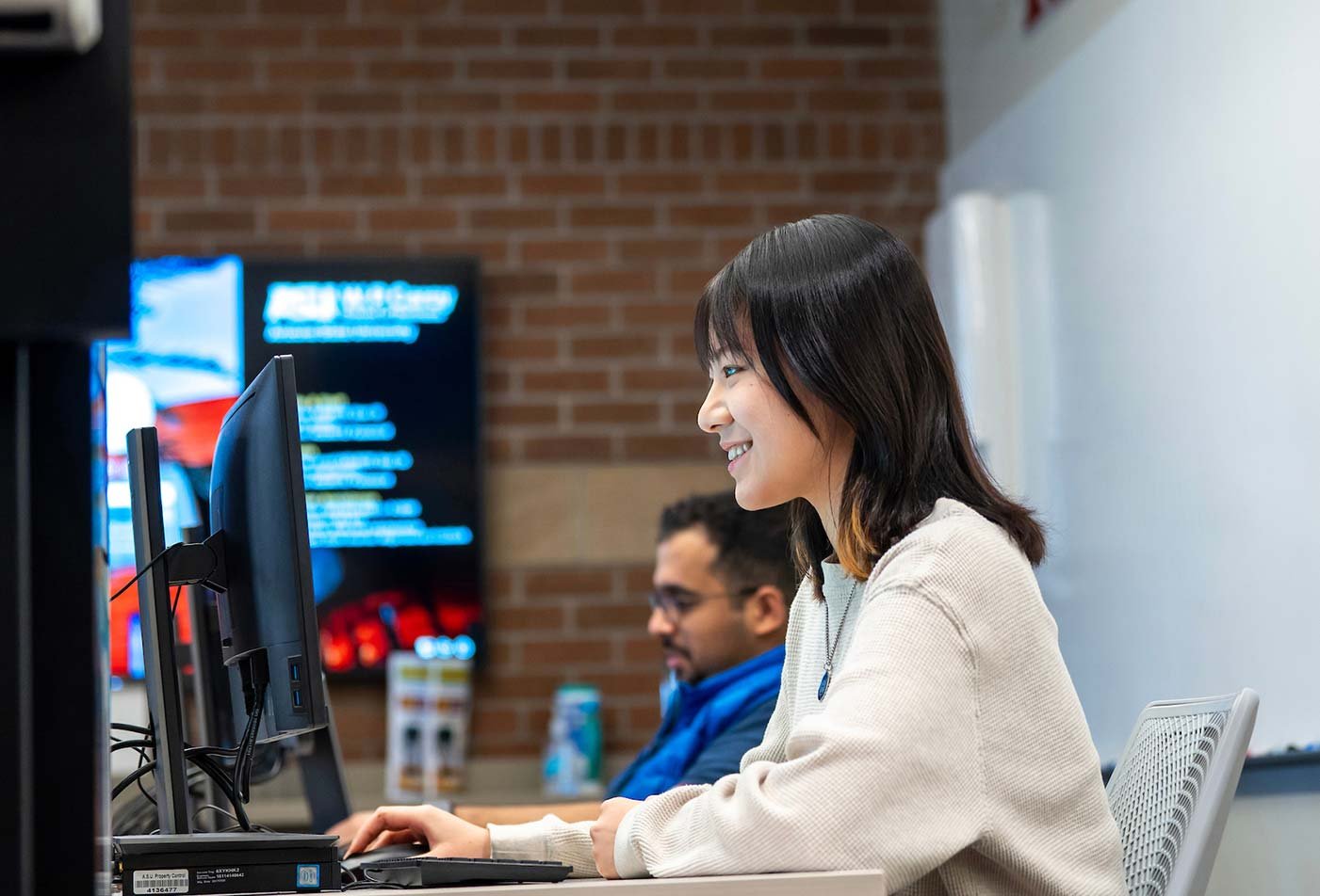Students work in a collaborative learning environment at computers, illustrating the interactive approach of ASU's MS in Global Logistics program.