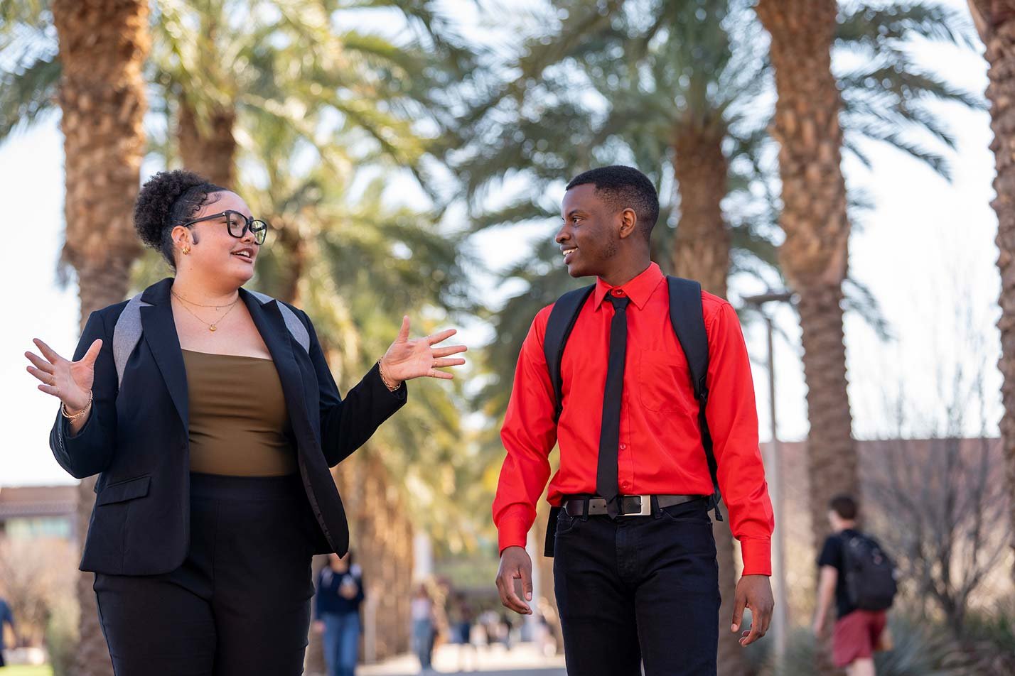Students engage in lively discussion while walking under palm trees on campus, showcasing networking opportunities in ASU's International Business Studies certificate program.