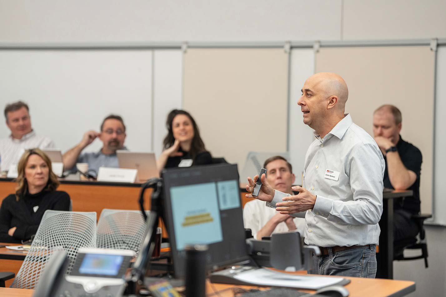 A speaker gestures during a presentation, conveying a collaborative atmosphere in ASU's PhD in Computer Information Systems program.