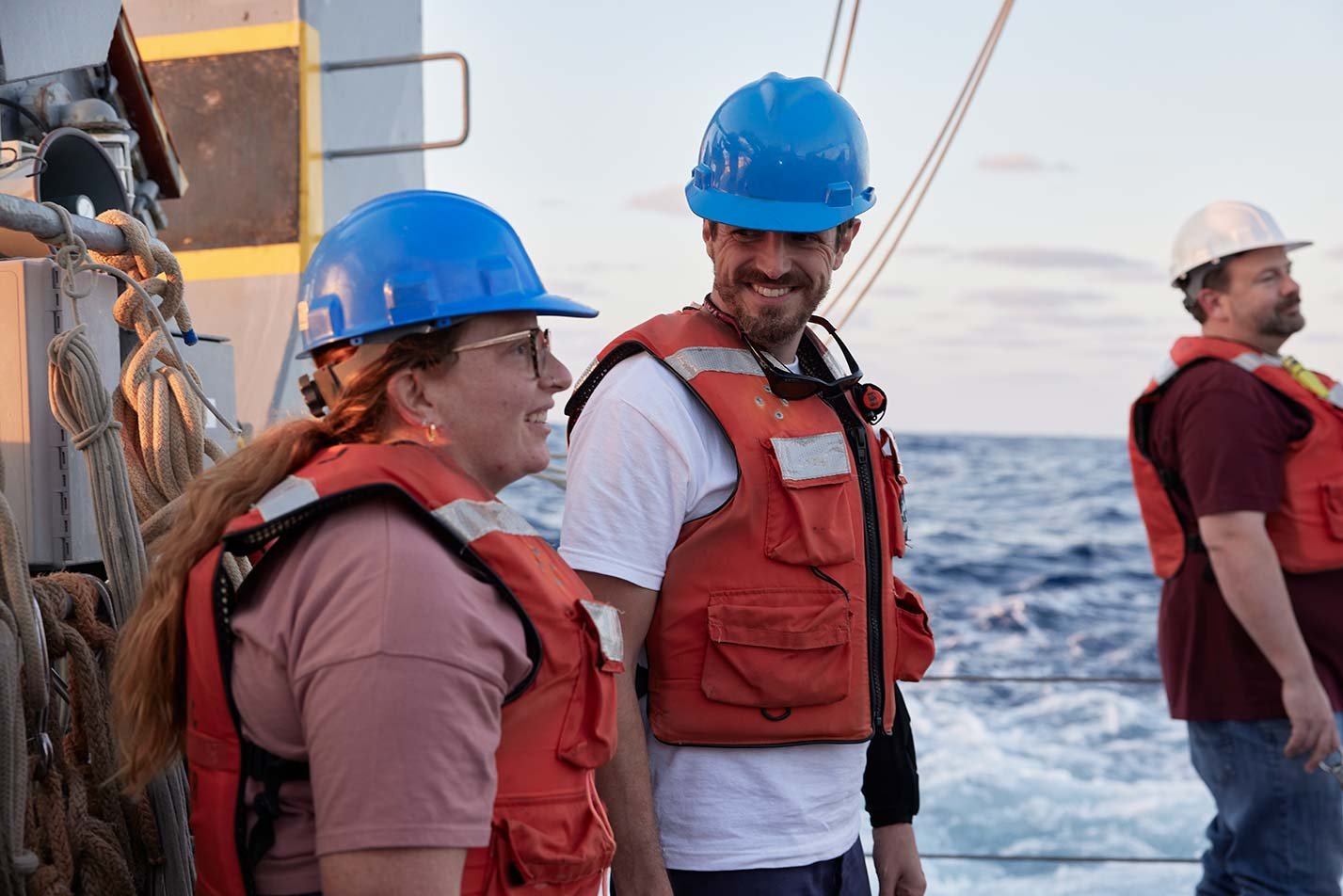 Individuals in safety gear aboard a boat look out at the ocean, demonstrating the field explored in ASU's Logistics (Maritime) program.