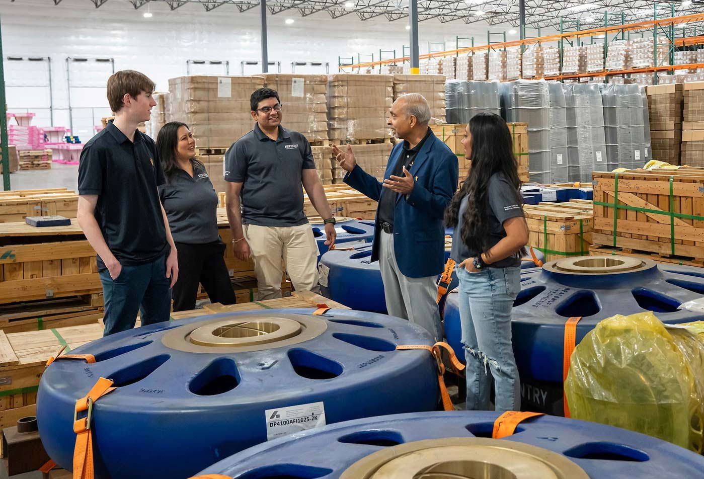 Standing in a warehouse environment, a class learns about logistics in a real-world scenario through in ASU's Supply Chain Management degree.
