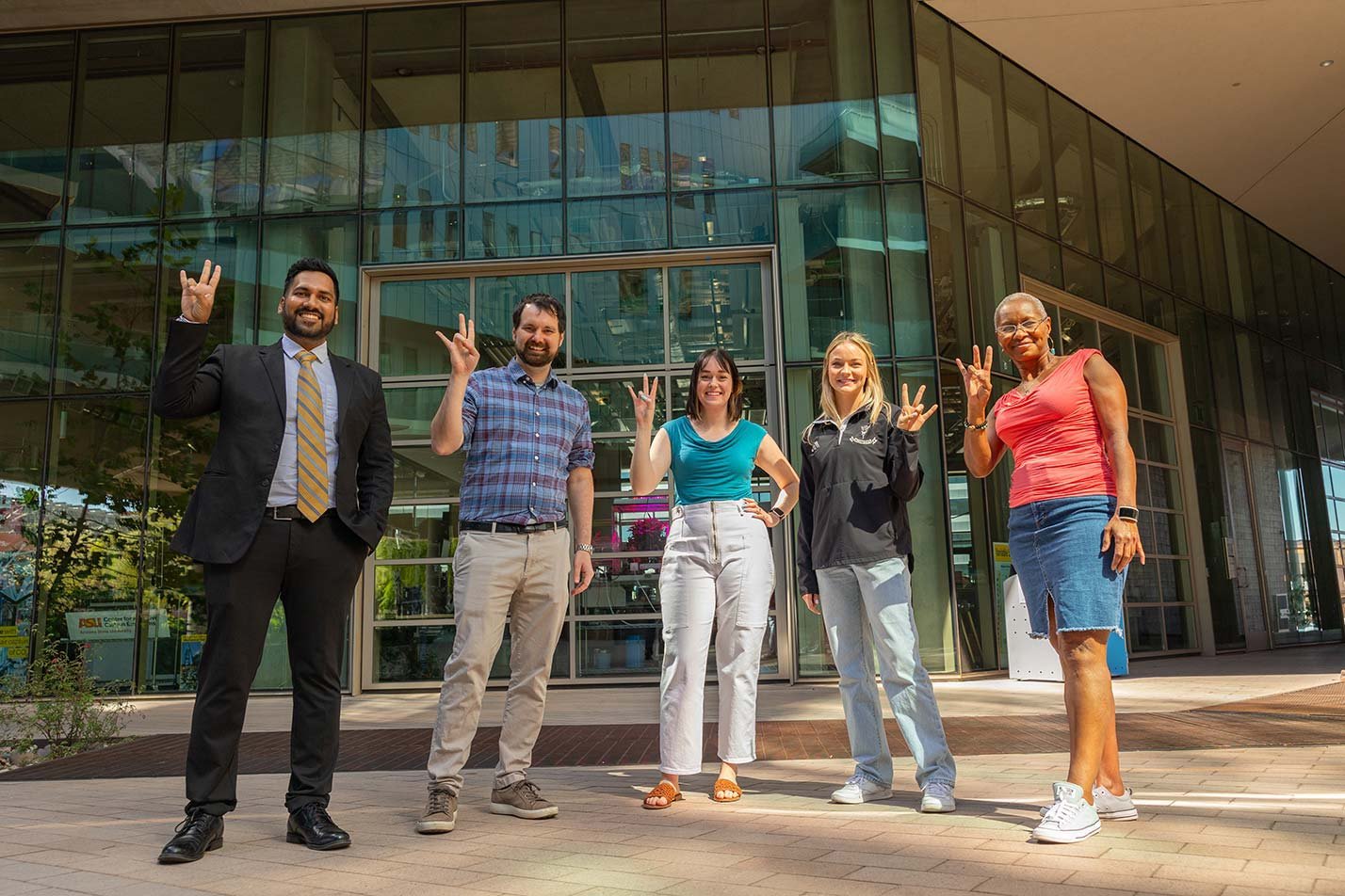 Students smile outside a modern building, showcasing the community gained in ASU's Supply Chain Management graduate certificate program.