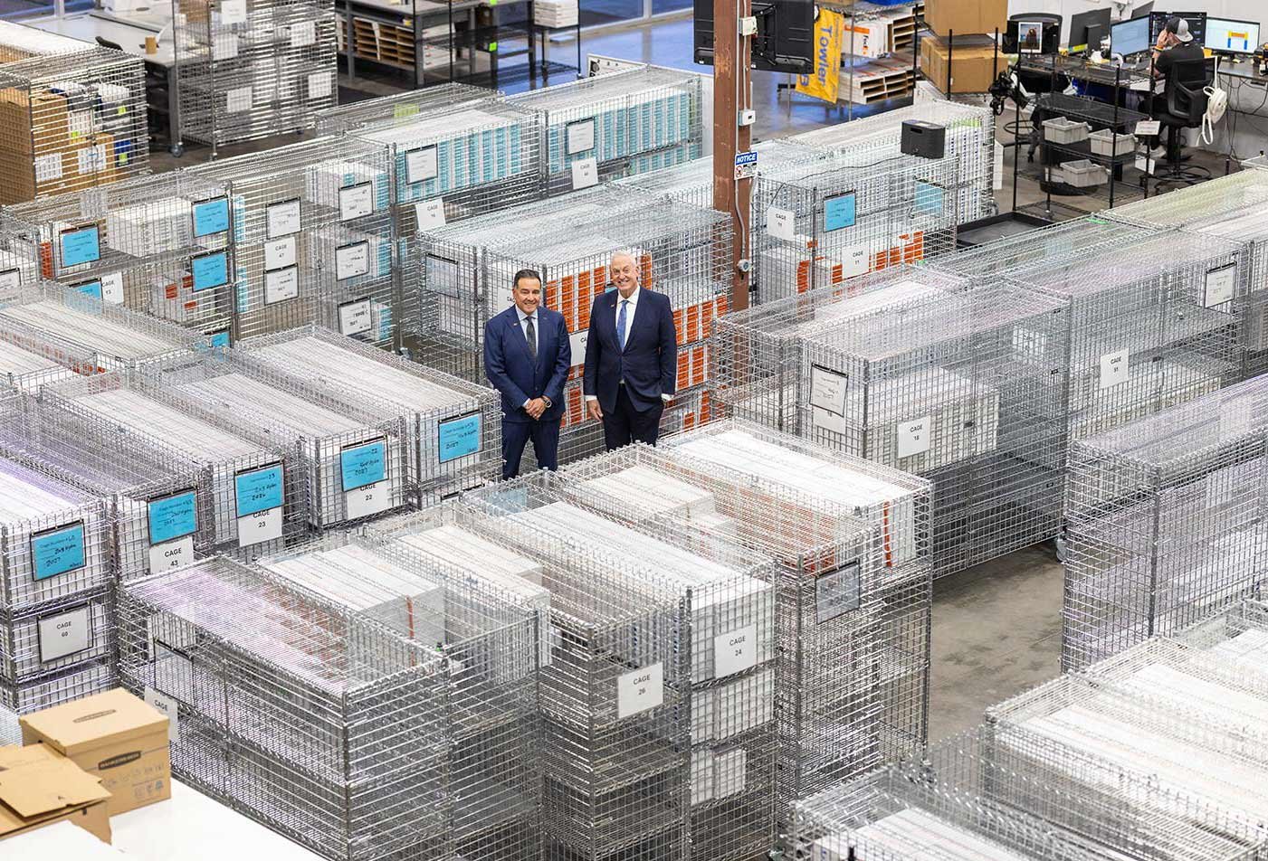 Two professionals stand among metal storage racks in a distribution center, showing real-world skills in ASU's Supply Chain Management and Engineering degree.