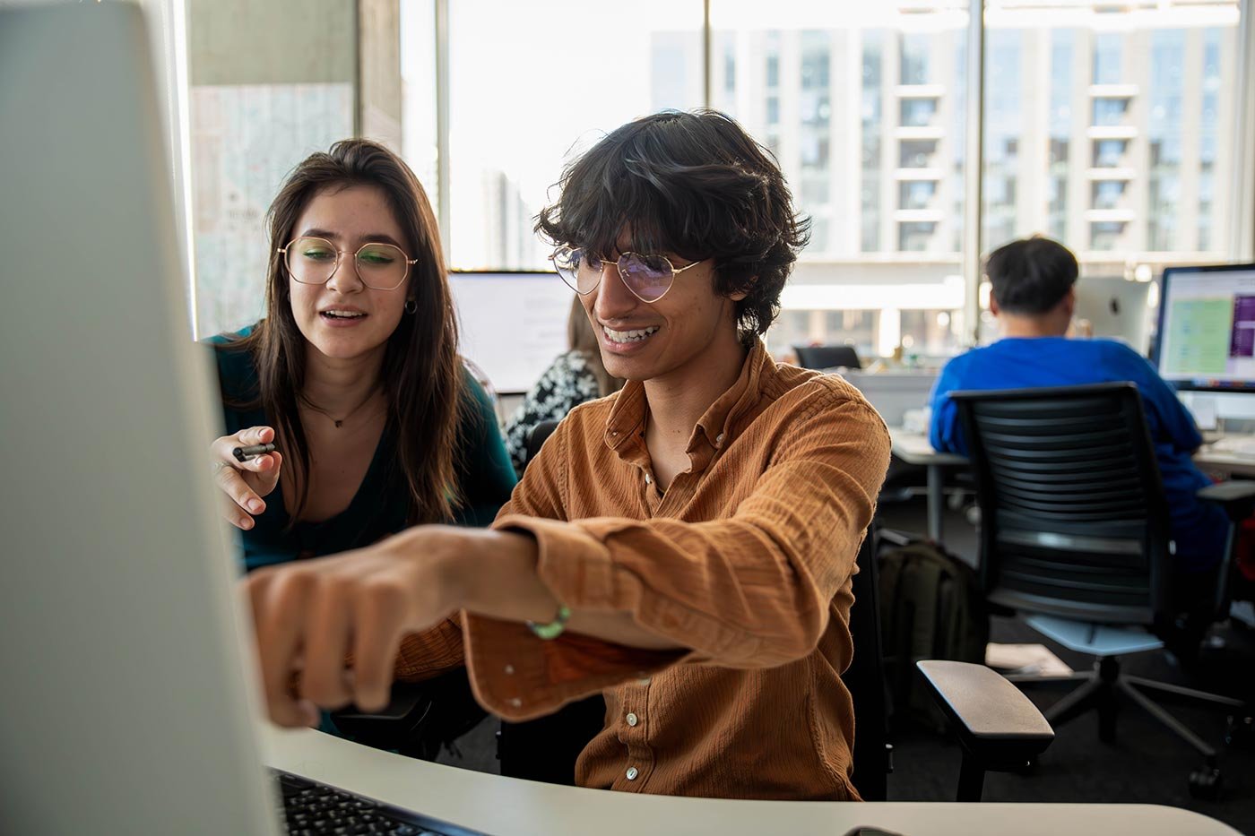 Two students collaborate on a project in an office setting, exemplifying teamwork in ASU's BS in Digital Strategy and Audience Engagement program.