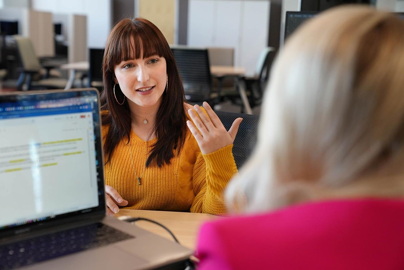Two students engage in conversation over a laptop, showcasing collaborative skills crucial for success in ASU's Digital Media Literacy program.