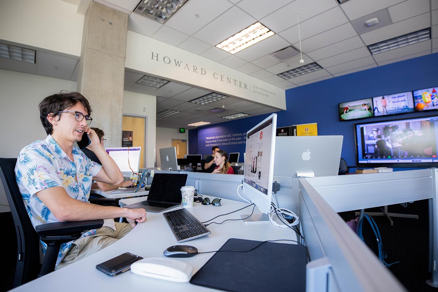 A student talks on the phone while working in the Howard Center for Investigative Journalism, where ASU's MA in Investigative Journalism program fosters hands-on learning.