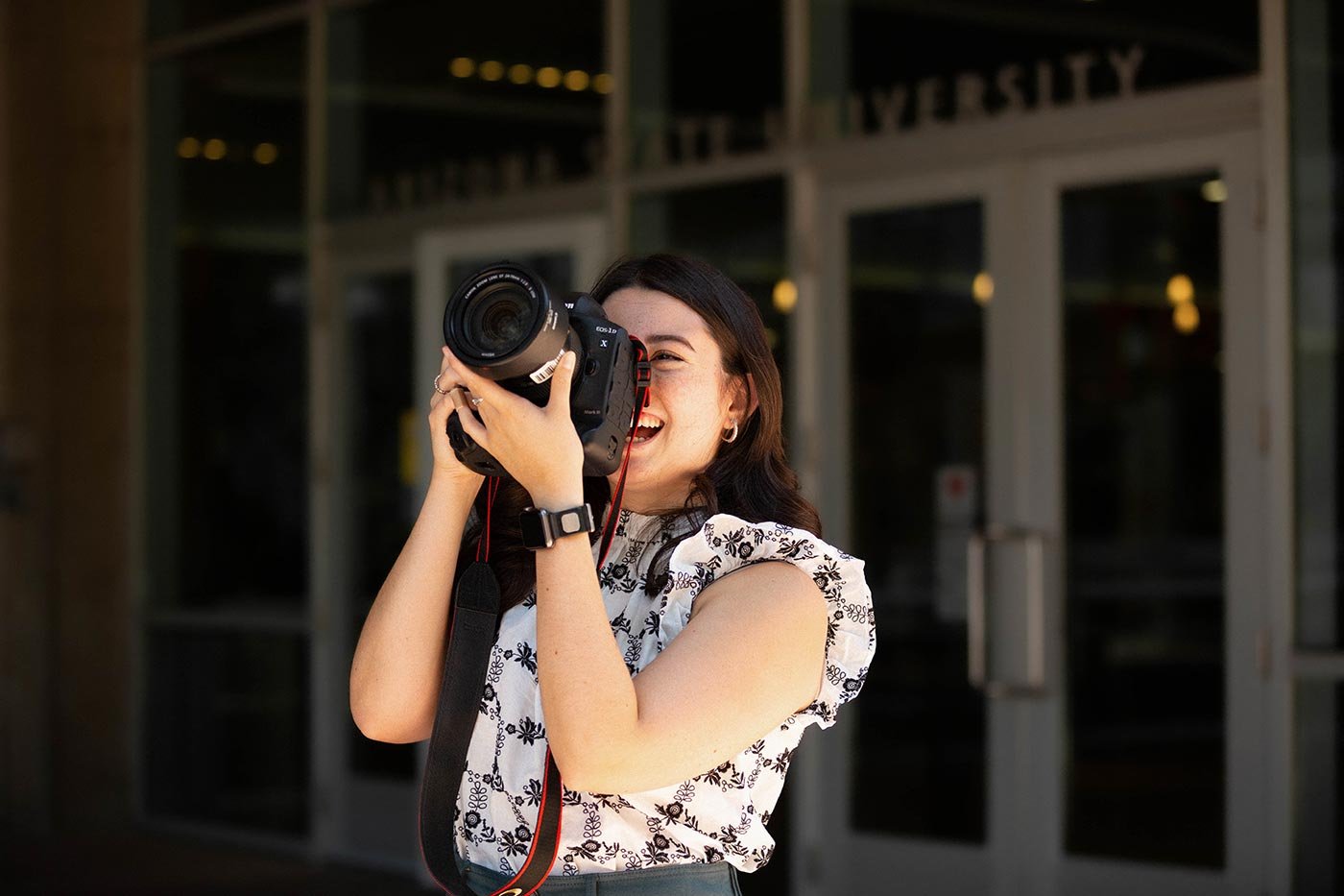 A student captures images with a camera outside Arizona State University, showcasing practical skills in the MMC in Mass Communication program.