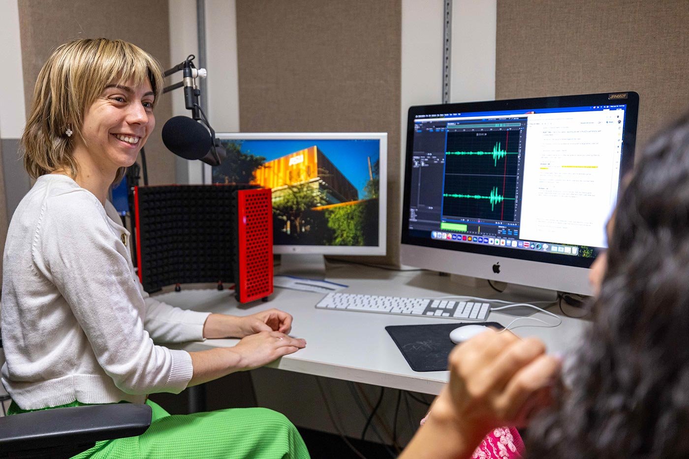 A student smiles while recording audio in a studio, representing hands-on learning in ASU’s MA in Science Communication program.