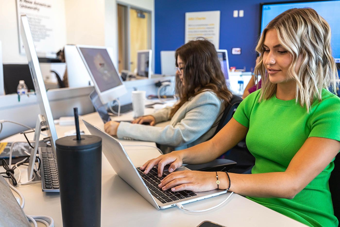 Students focus on a project at a computer station, illustrating dynamic learning in ASU's BA in Sports Strategic Communication program.