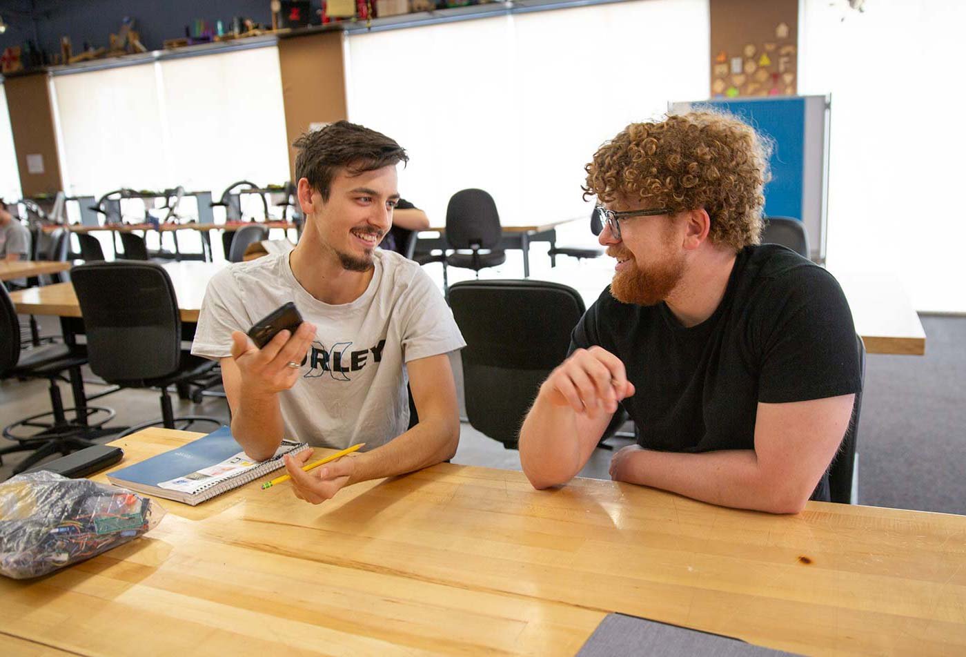 Two students discuss ideas in a collaborative makerspace, reflecting teamwork in ASU's Human Systems Engineering, MS program.