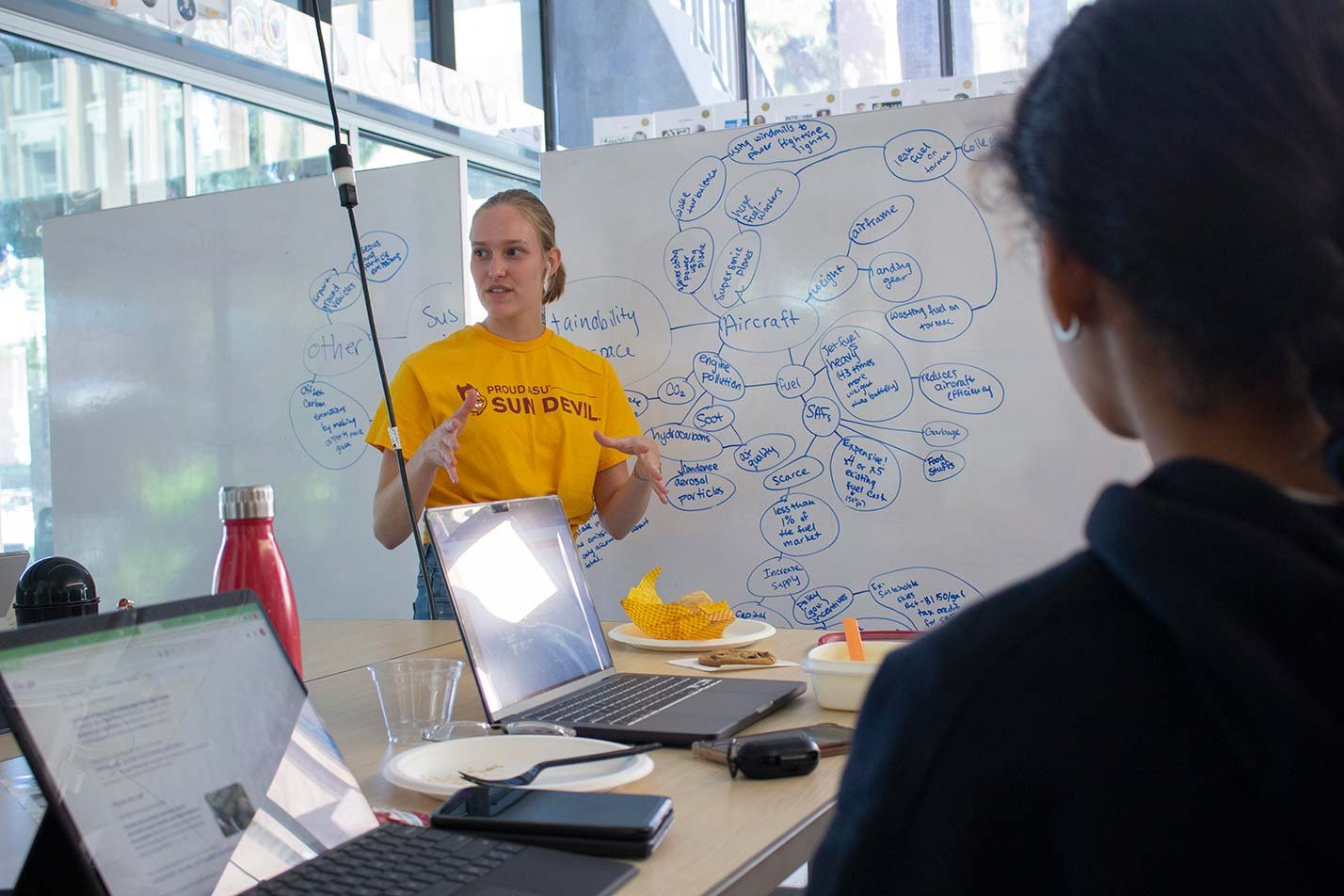 A student presents ideas at a brainstorming whiteboard, showcasing teamwork in ASU's Aerospace Engineering, PhD program.