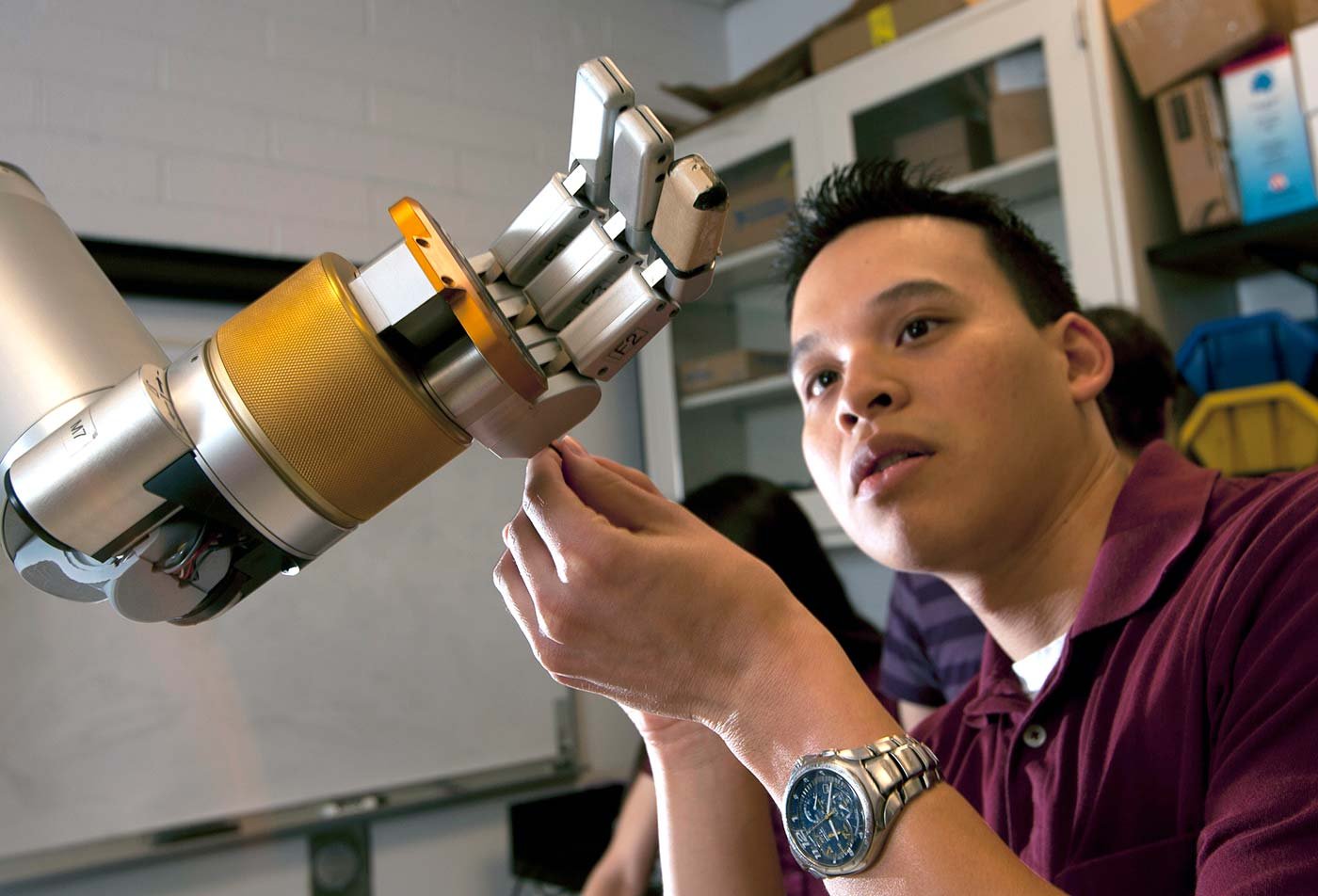 A student repairs a mechanical hand, demonstrating techniques central to ASU's MS in Artificial Intelligence Engineering (Mechanical Engineering) program.