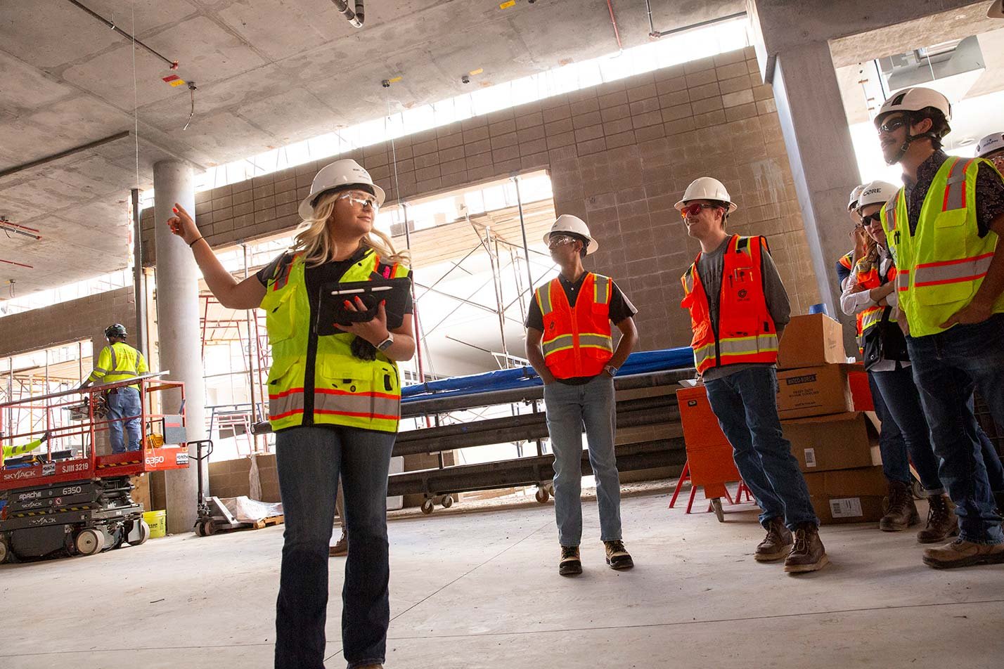 Students in hard hats gather at a site as one leads a discussion, highlighting expertise gained in ASU's Artificial Intelligence Engineering (Sustainable Engineering and Built Environment) degree.
