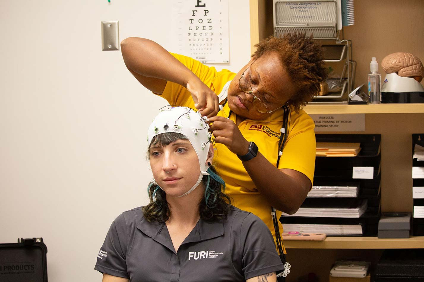 A researcher adjusts an EEG cap on a participant in a lab, demonstrating hands-on learning in ASU's Biomedical Engineering PhD program.