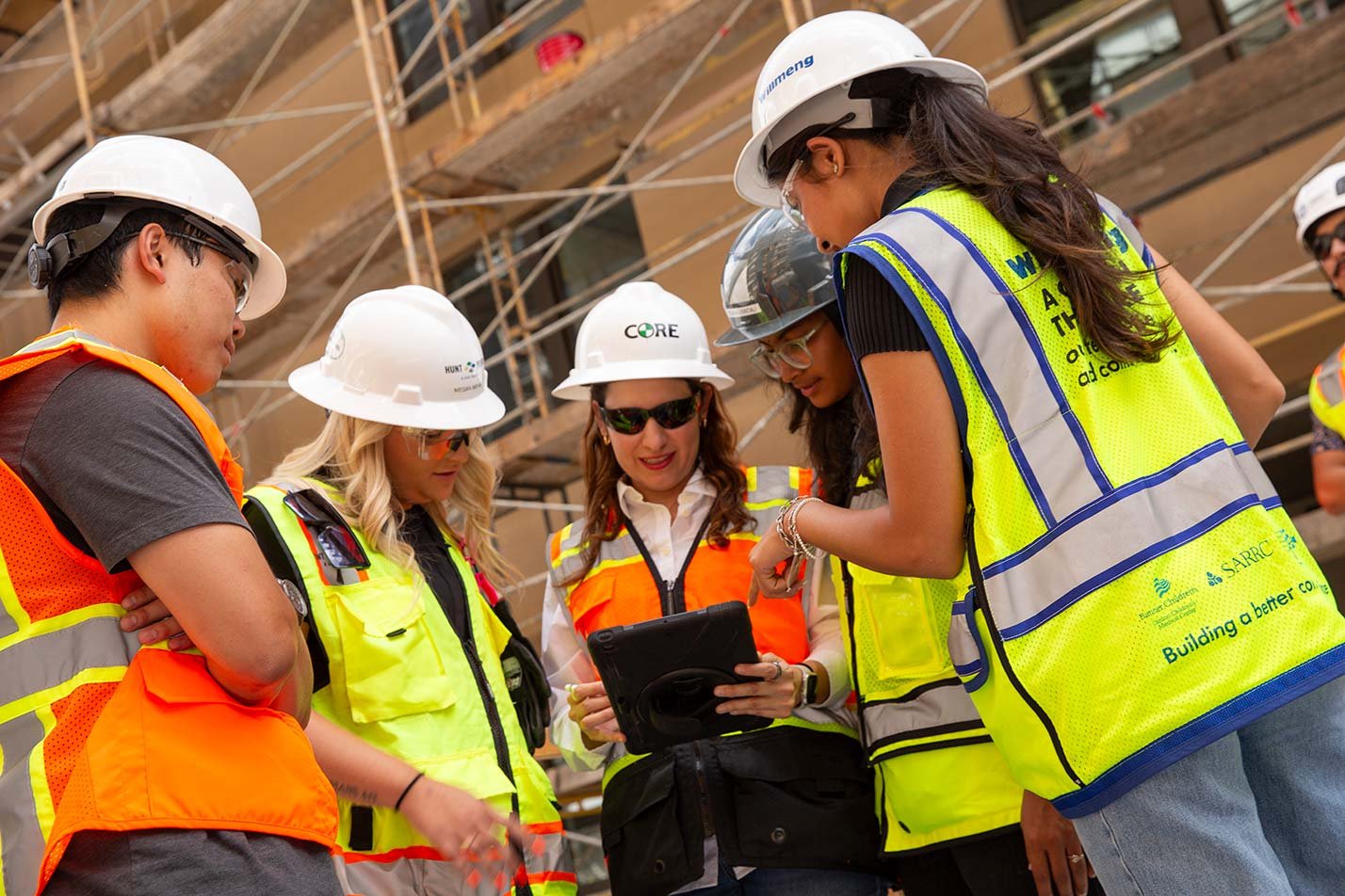 Students and a professor review a tablet at a construction site, showcasing hands-on learning in ASU's Civil, Environmental and Sustainable Engineering degree.