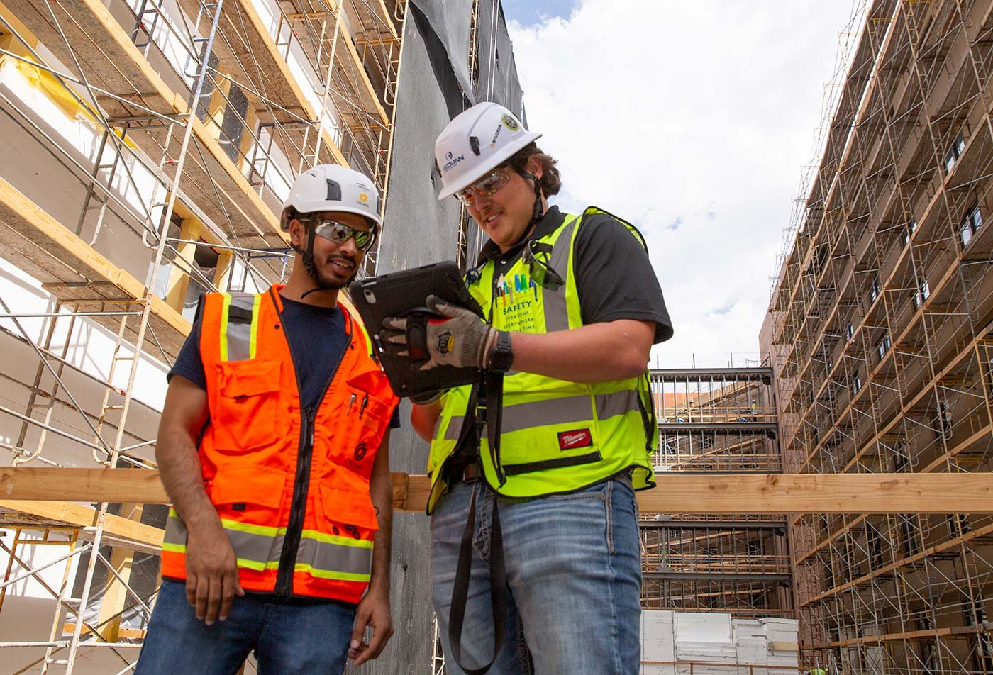 Two students collaborate on a construction site, showcasing practical skills in ASU's Construction Management program.