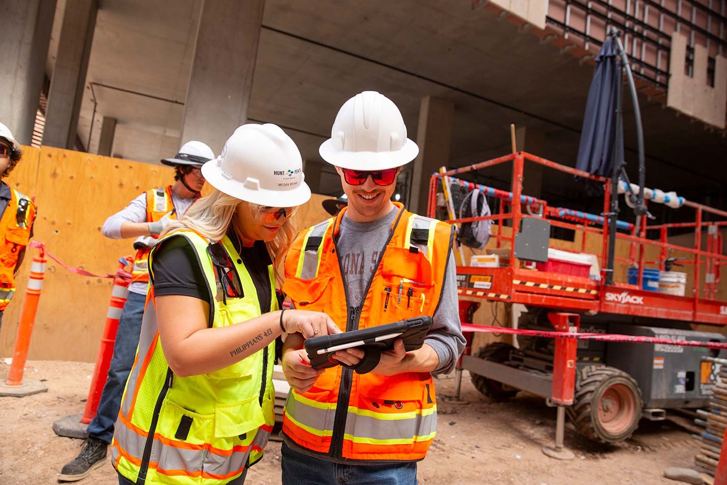 Two construction professionals examine a tablet at a job site, emphasizing practical skills in ASU's Construction Engineering degree.