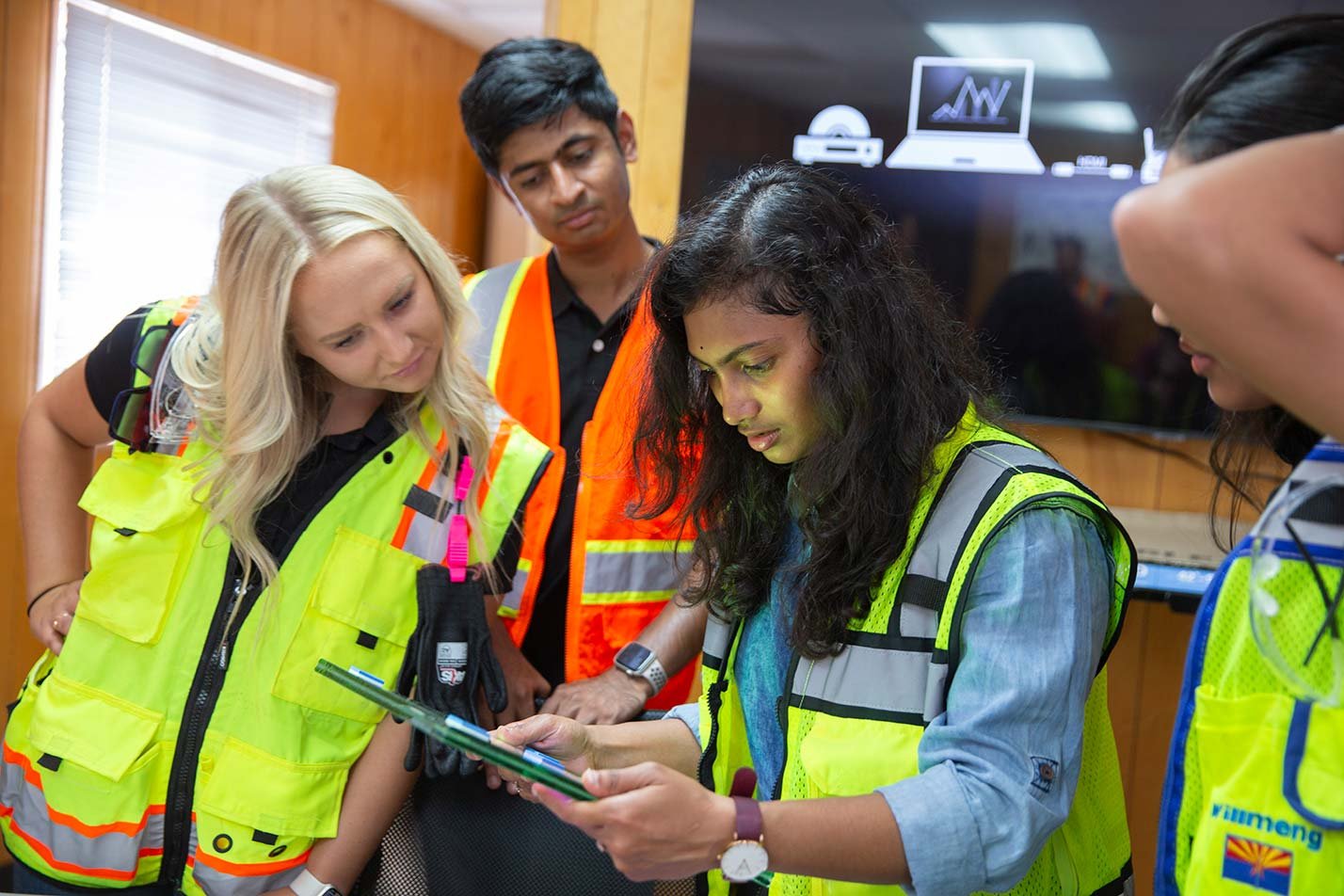 Students in safety vests review plans in a trailer, showcasing practical experience in ASU's Construction Management and Technology program.