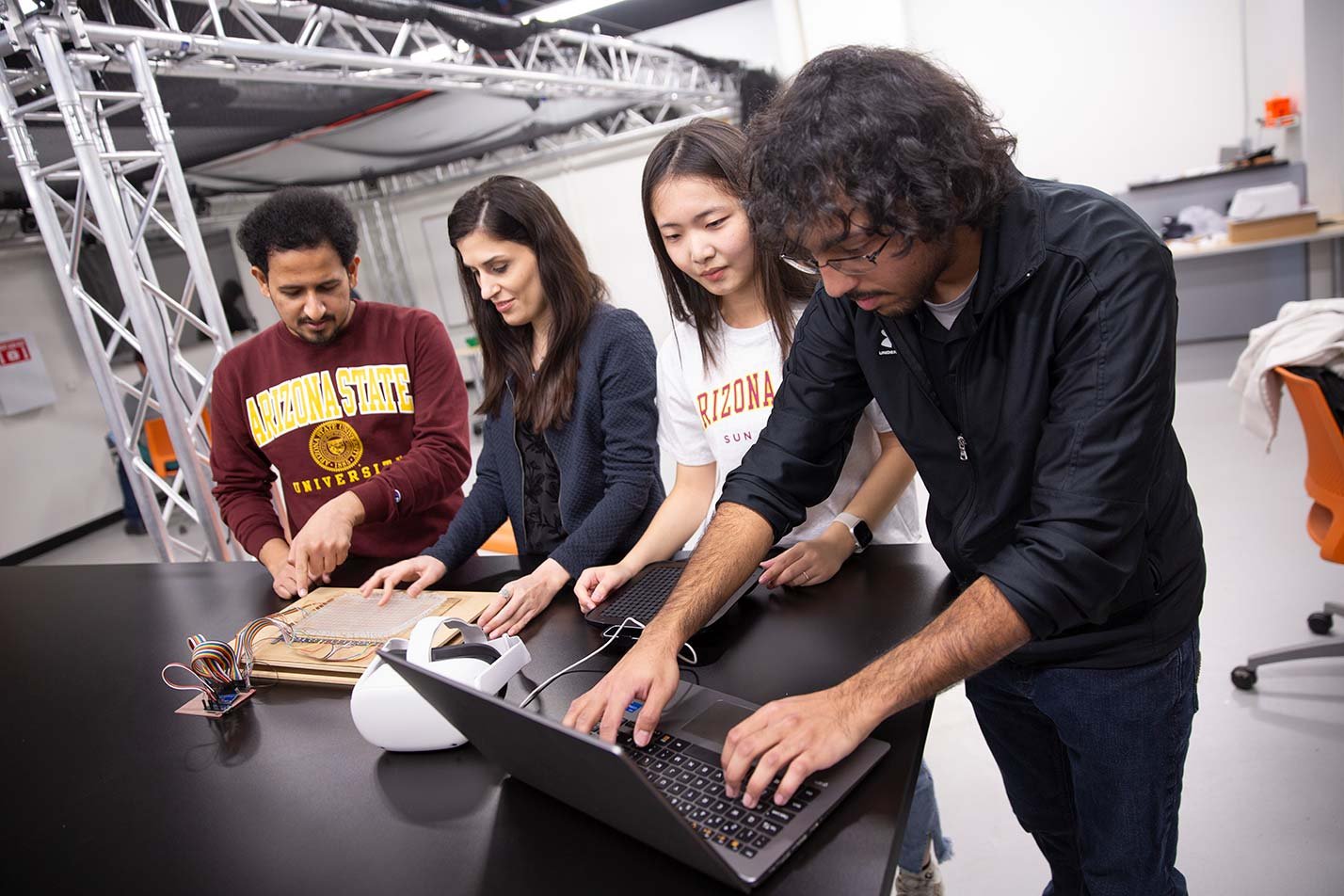 Students collaborate around a table, integrating technology and coding in a hands-on project for ASU's BA in Computer Science degree.
