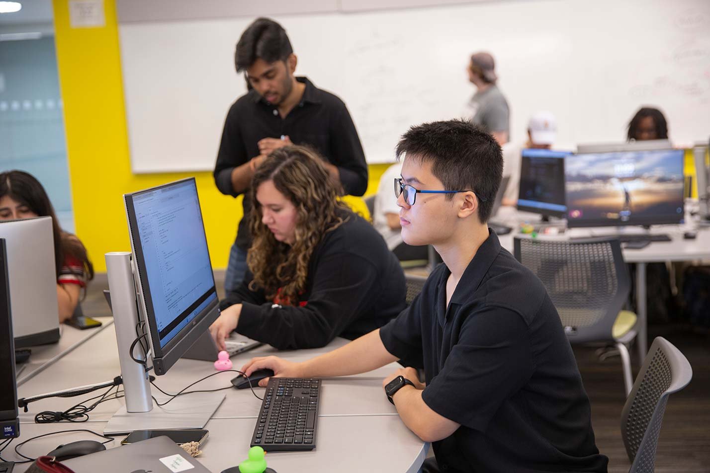 Students focus on coding in a modern classroom, exemplifying collaborative learning in ASU's Computer Science degree.