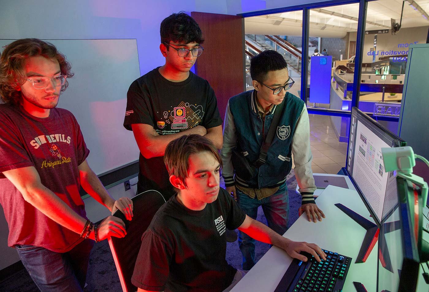 Students collaborate around a computer, engaging in coding, reflecting practical skills in ASU's Computer Science (Cybersecurity) degree.