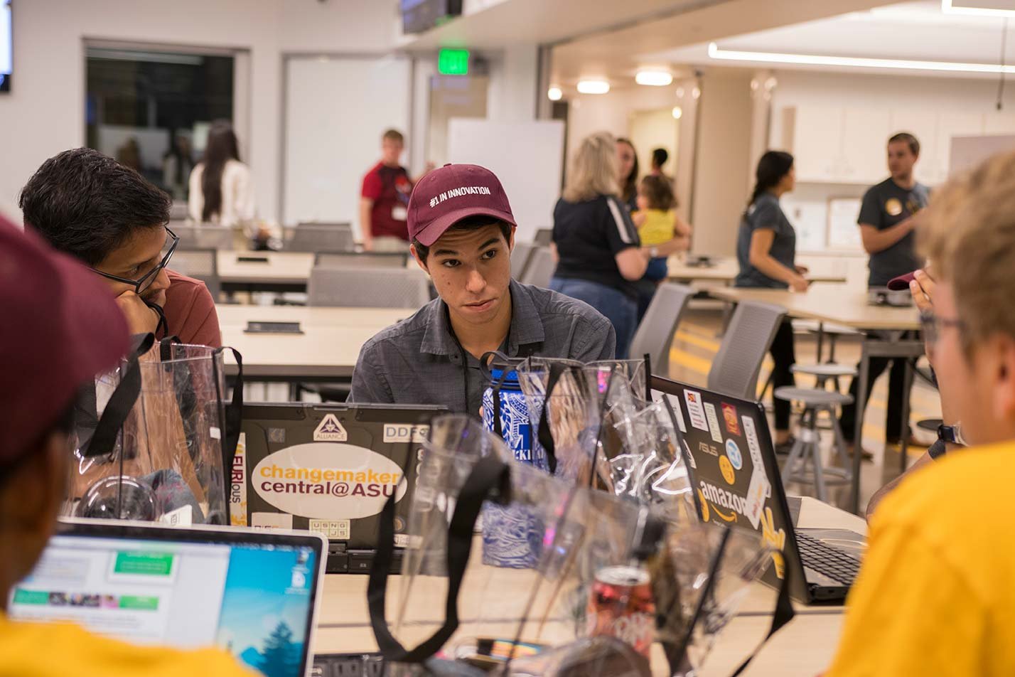 A team collaborates around laptops in an innovation space, developing secure computing solutions in ASU's Cybersecurity (Graduate Certificate).
