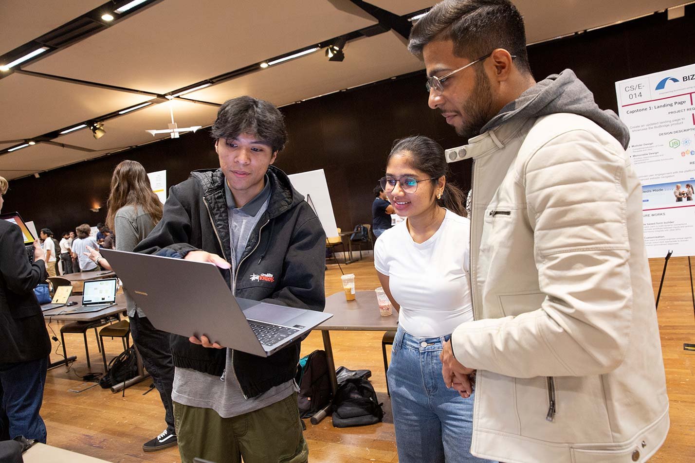 Students present a project on a laptop at a showcase in ASU's Data Science, Analytics and Engineering (Computing and Decision Analytics), MS degree.