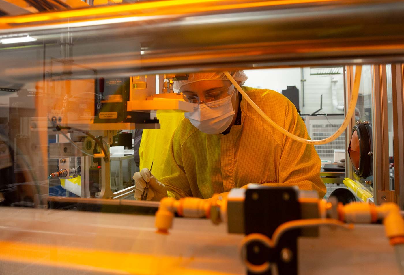 Students in protective gear work on solar panels in a clean room, reflecting hands-on experiences in ASU's Electrical Engineering degree.