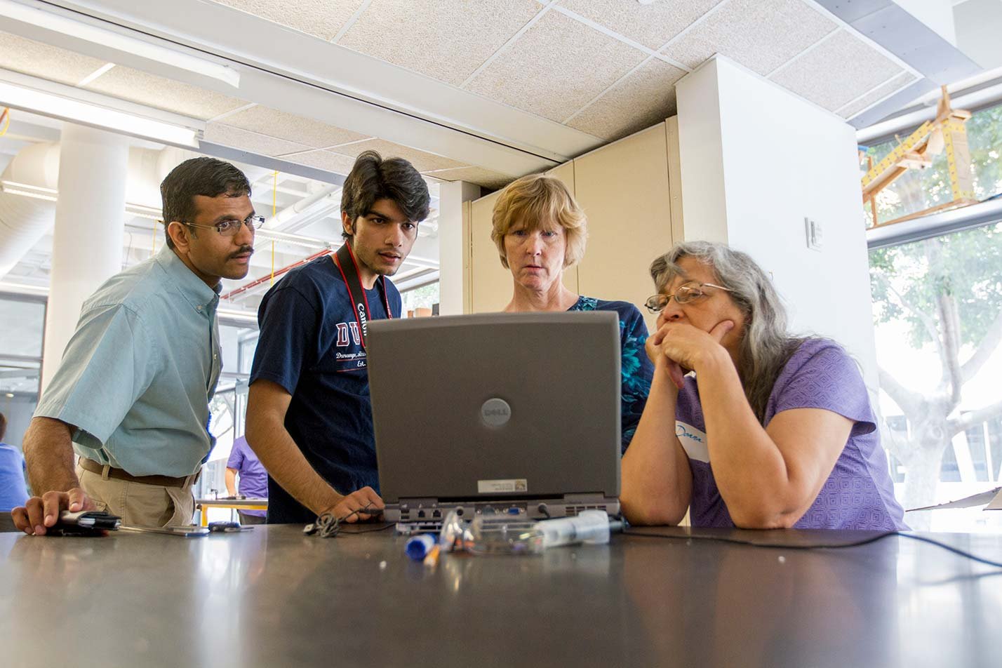 Faculty and students collaborate around a laptop, reflecting mentorship in ASU's Engineering Education Systems and Design, PhD program.