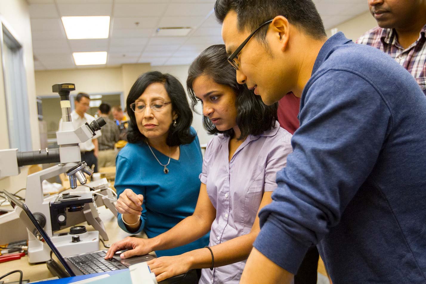 Researchers examine data from a microscope, demonstrating hands-on investigation in ASU's Engineering, DEng program.