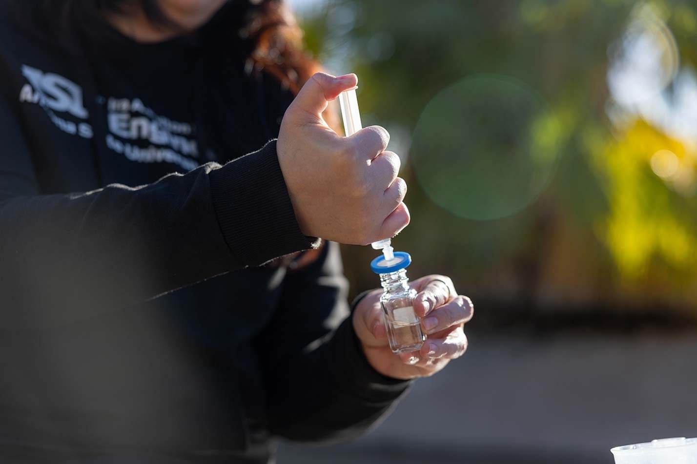 A researcher collects a water sample, experiencing fieldwork in ASU's Environmental and Resource Management (Water Management), MS program.