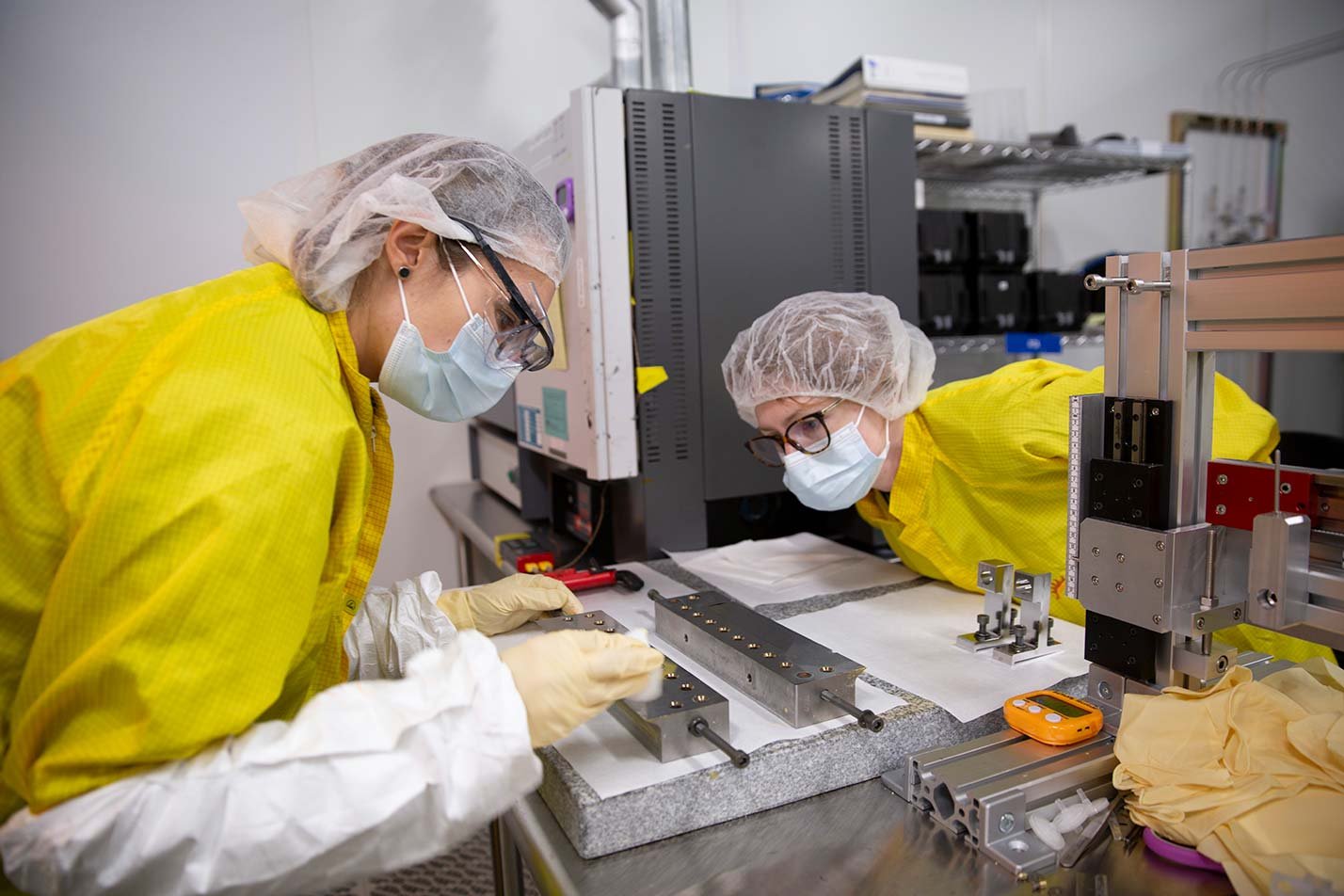 Two students in yellow protective coats examine components on a table, highlighting hands-on learning in ASU's Engineering Science (Microelectronics) degree.