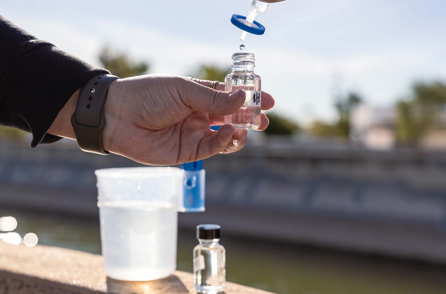 A researcher collects a water sample for analysis, demonstrating field-based research in ASU's Environmental Engineering, PhD program.