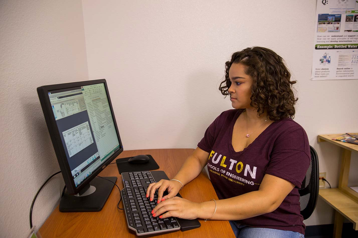 A student works at a computer desk, focused on data displayed on screen, demonstrating analytical skills in ASU's Human Systems Engineering degree.