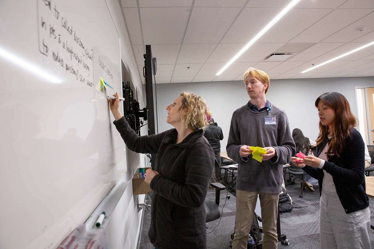 A team brainstorms ideas on a whiteboard, reflecting collaborative problem-solving in ASU's Innovations in Medical and Patient Care Technologies, MS program.
