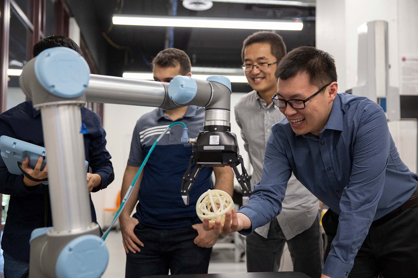 Researchers test a robotic arm in a laboratory, showcasing process innovation in ASU's Industrial Engineering, MS program.