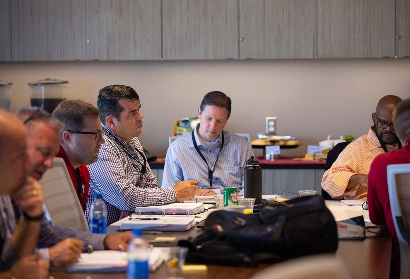 Professionals work together a confrence table, demonstrating process improvement in ASU's Lean Six Sigma Black Belt (Graduate Certificate).