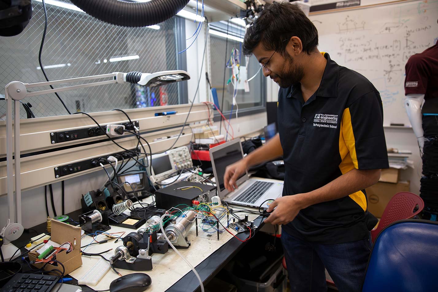 A student assembles components at a lab bench, showcasing hands-on learning in ASU's Mechanical Engineering (Computational Mechanics) degree.